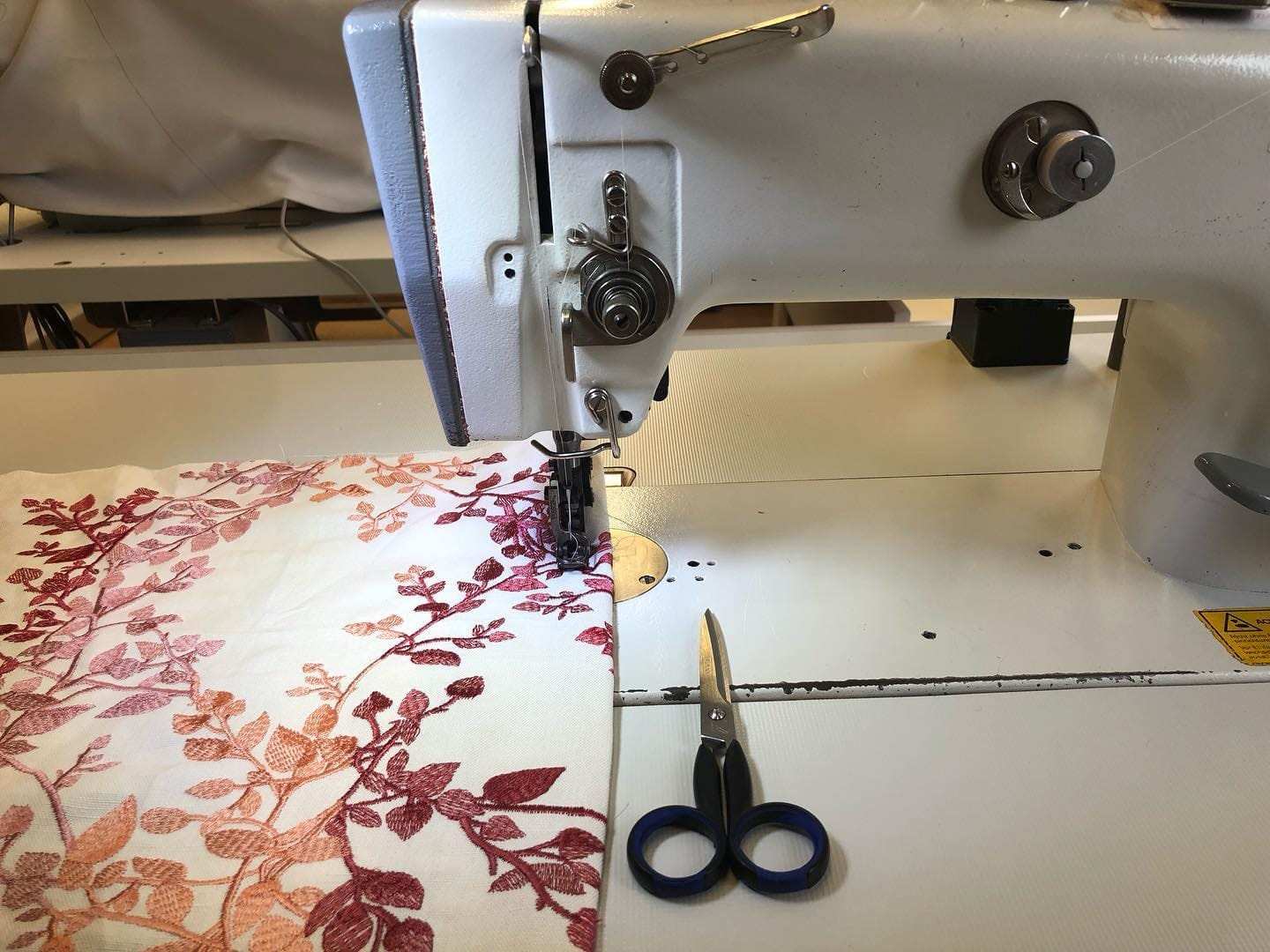 Embroidered fabric at the industrial sewing machine, shears beside it